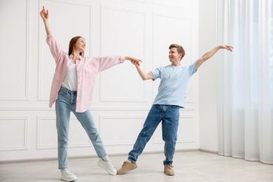 Photo of Happy couple dancing together near white wall at home