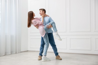 Photo of Happy couple dancing together near white wall at home