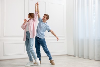 Photo of Happy couple dancing together near white wall at home