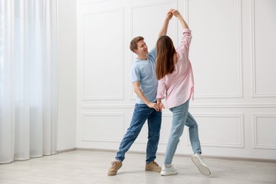Photo of Happy couple dancing together near white wall at home