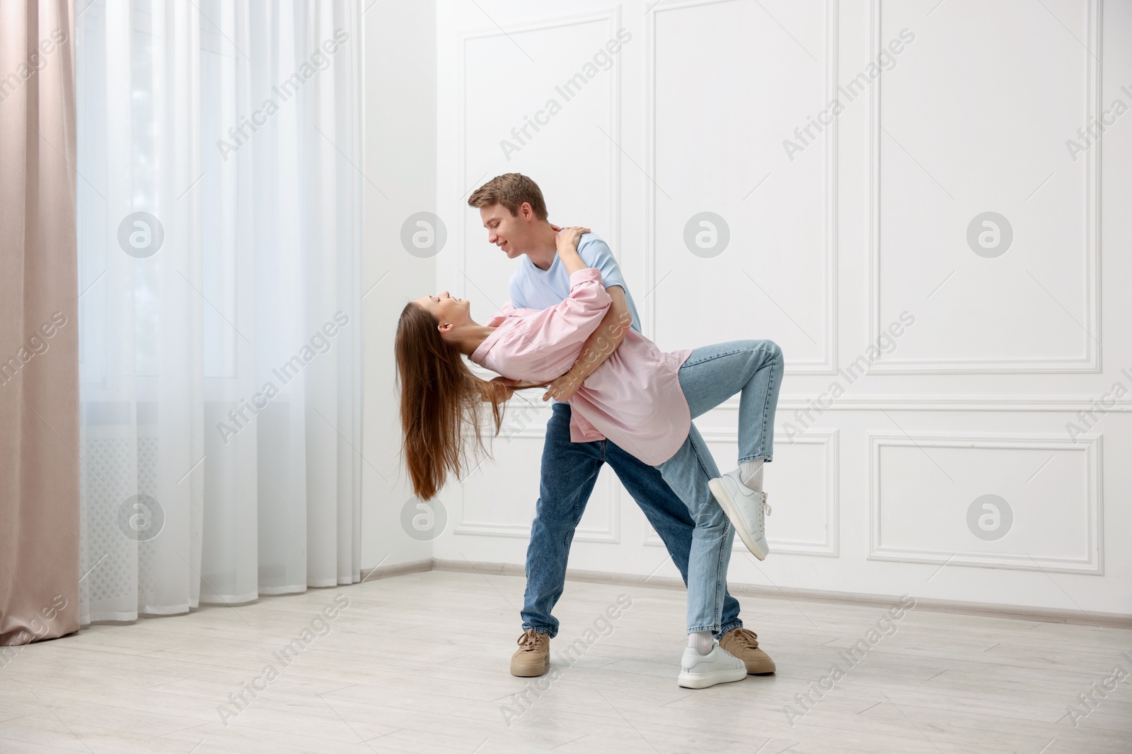 Happy couple dancing together near white wall at home Photo of Happy couple dancing together near white wall at home