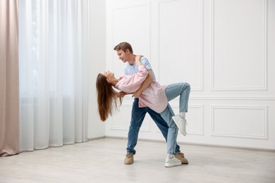 Photo of Happy couple dancing together near white wall at home