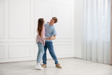 Photo of Happy couple dancing together near white wall at home