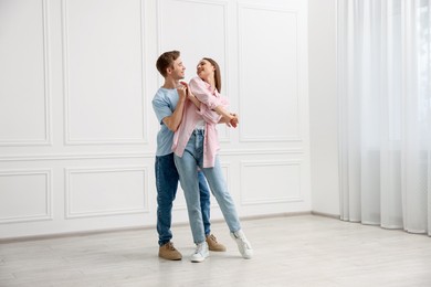 Photo of Happy couple dancing together near white wall at home