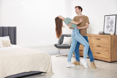 Photo of Happy young couple dancing together in bedroom
