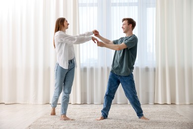 Photo of Happy young couple dancing together at home