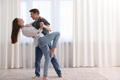 Photo of Happy young couple dancing together at home. Space for text