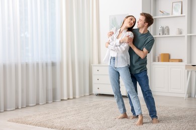 Photo of Happy young couple dancing together at home. Space for text