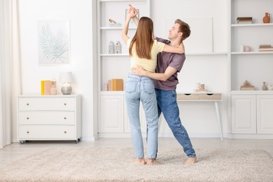 Photo of Happy young couple dancing together at home. Space for text