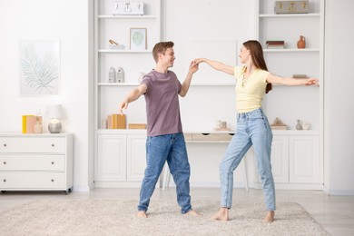Photo of Happy young couple dancing together at home. Space for text
