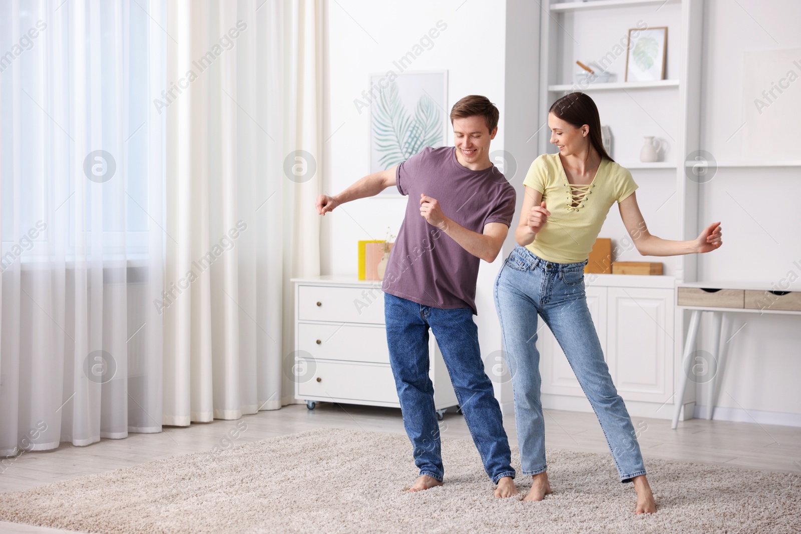 Happy young couple dancing together at home. Space for text Photo of Happy young couple dancing together at home. Space for text