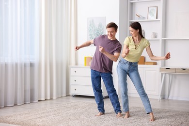 Photo of Happy young couple dancing together at home. Space for text