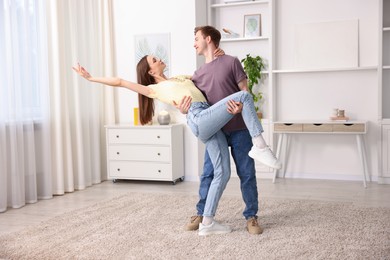Photo of Carefree young couple dancing together at home