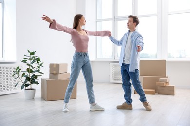 Photo of Young couple dancing and cardboard boxes at home. Moving day
