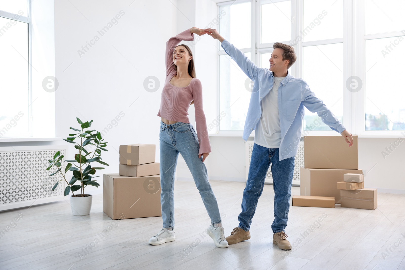 Happy young couple dancing and cardboard boxes at home. Moving day Photo of Happy young couple dancing and cardboard boxes at home. Moving day