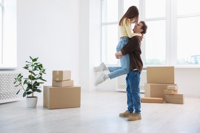Photo of Happy young couple dancing and cardboard boxes at home. Moving day