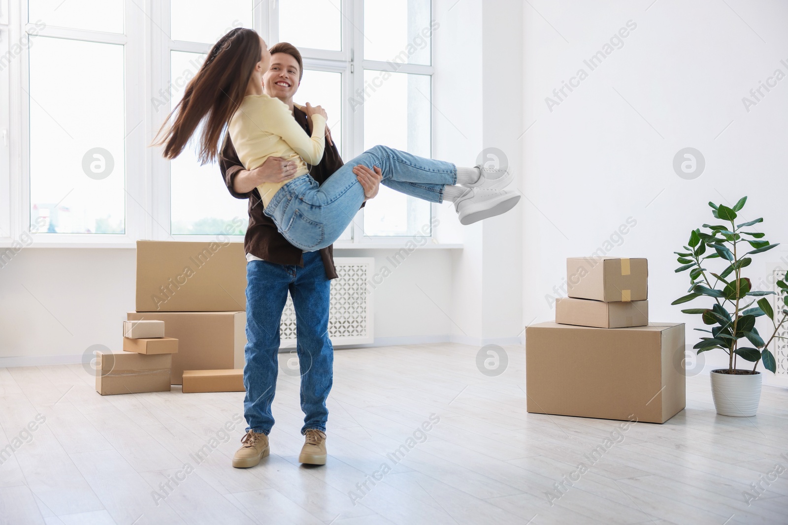 Photo of Happy young couple dancing and cardboard boxes at home. Moving day