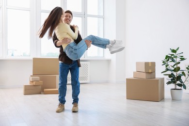 Photo of Happy young couple dancing and cardboard boxes at home. Moving day