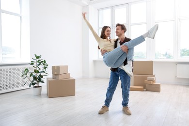 Photo of Happy young couple dancing and cardboard boxes at home. Moving day