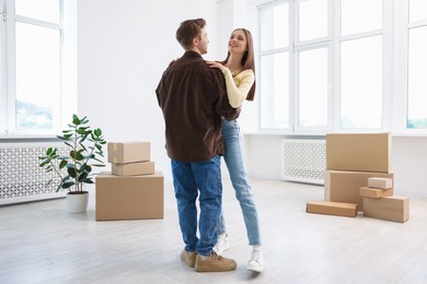 Photo of Happy young couple dancing and cardboard boxes at home. Moving day