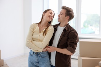 Photo of Happy young couple dancing and cardboard boxes at home. Moving day