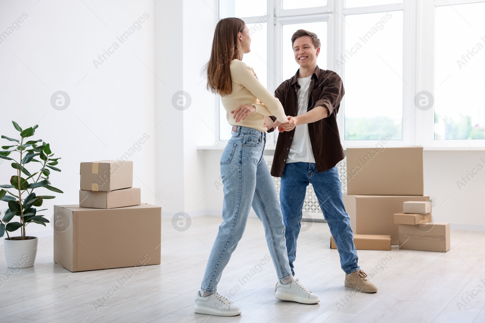 Happy young couple dancing among moving boxes at home Photo of Happy young couple dancing among moving boxes at home