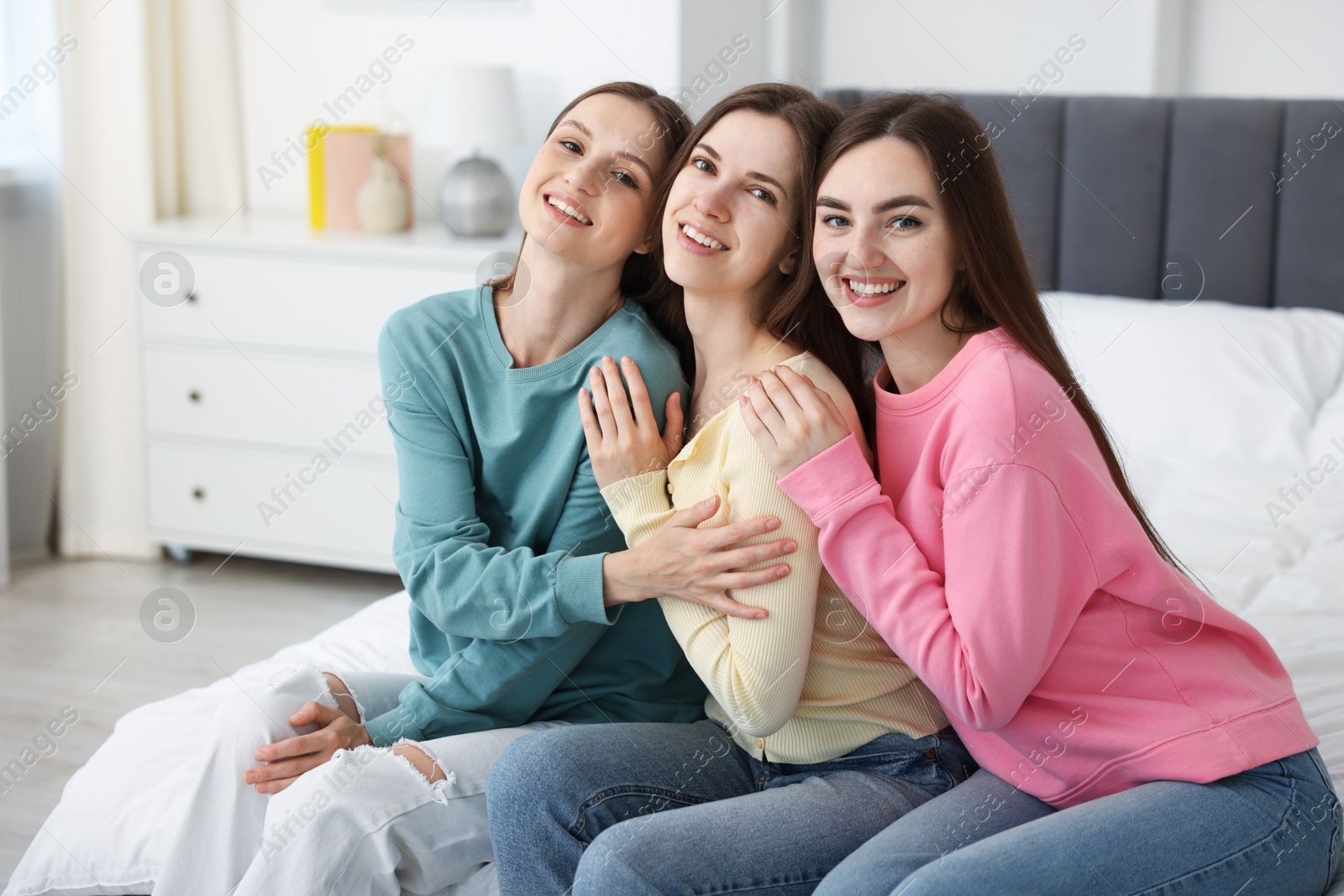 Happy friends hugging each other on bed at home Photo of Happy friends hugging each other on bed at home