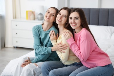 Photo of Happy friends hugging each other on bed at home