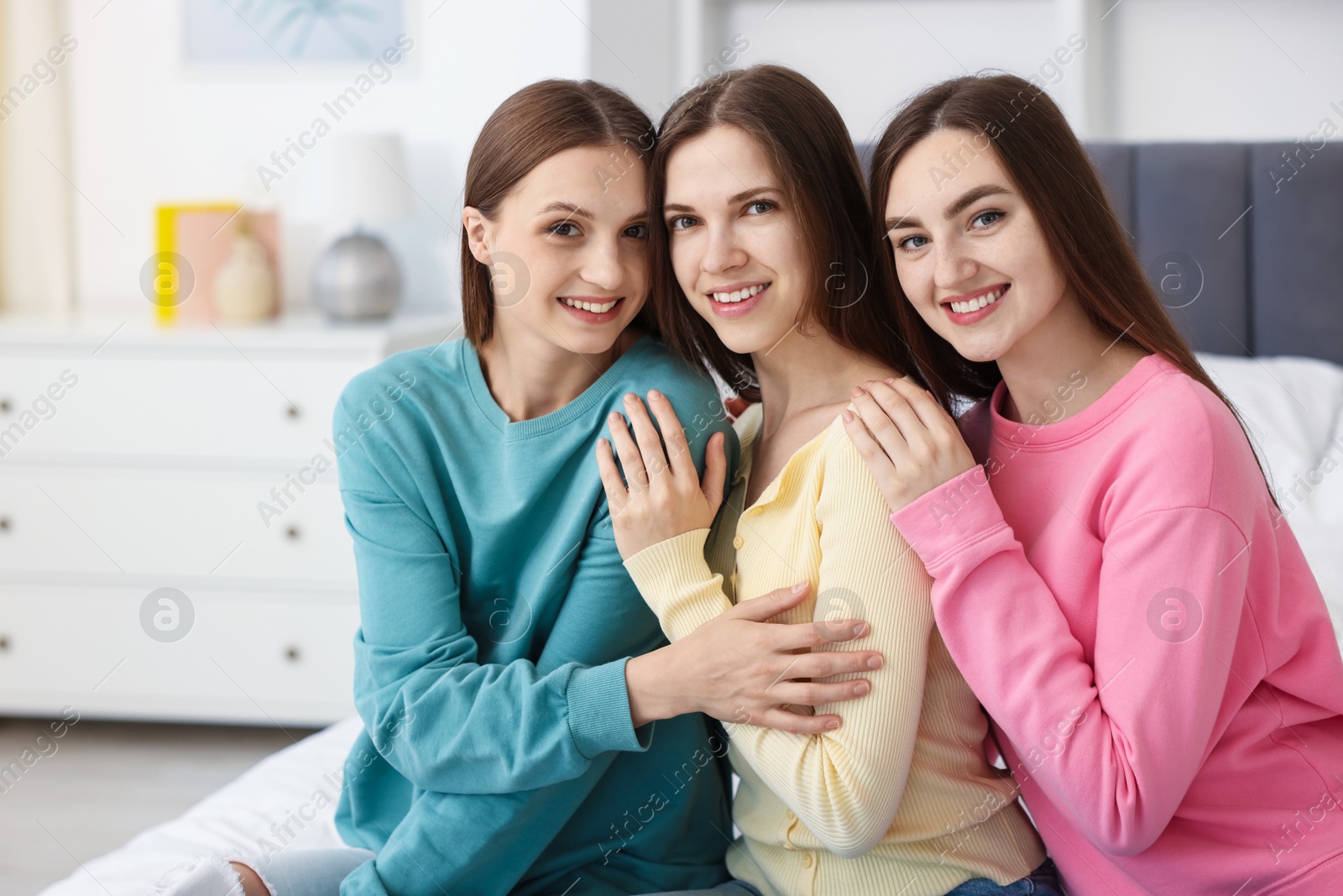 Photo of Happy friends hugging each other on bed at home