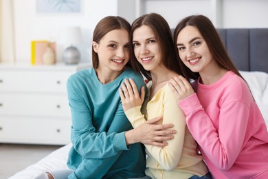 Photo of Happy friends hugging each other on bed at home