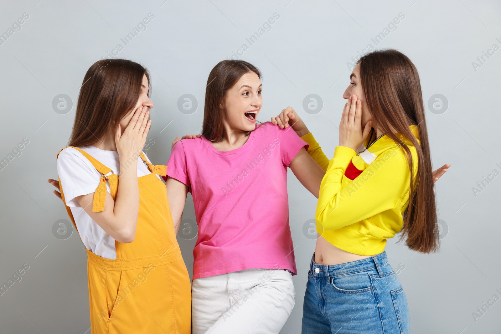 Friends hugging each other on light grey background Photo of Friends hugging each other on light grey background