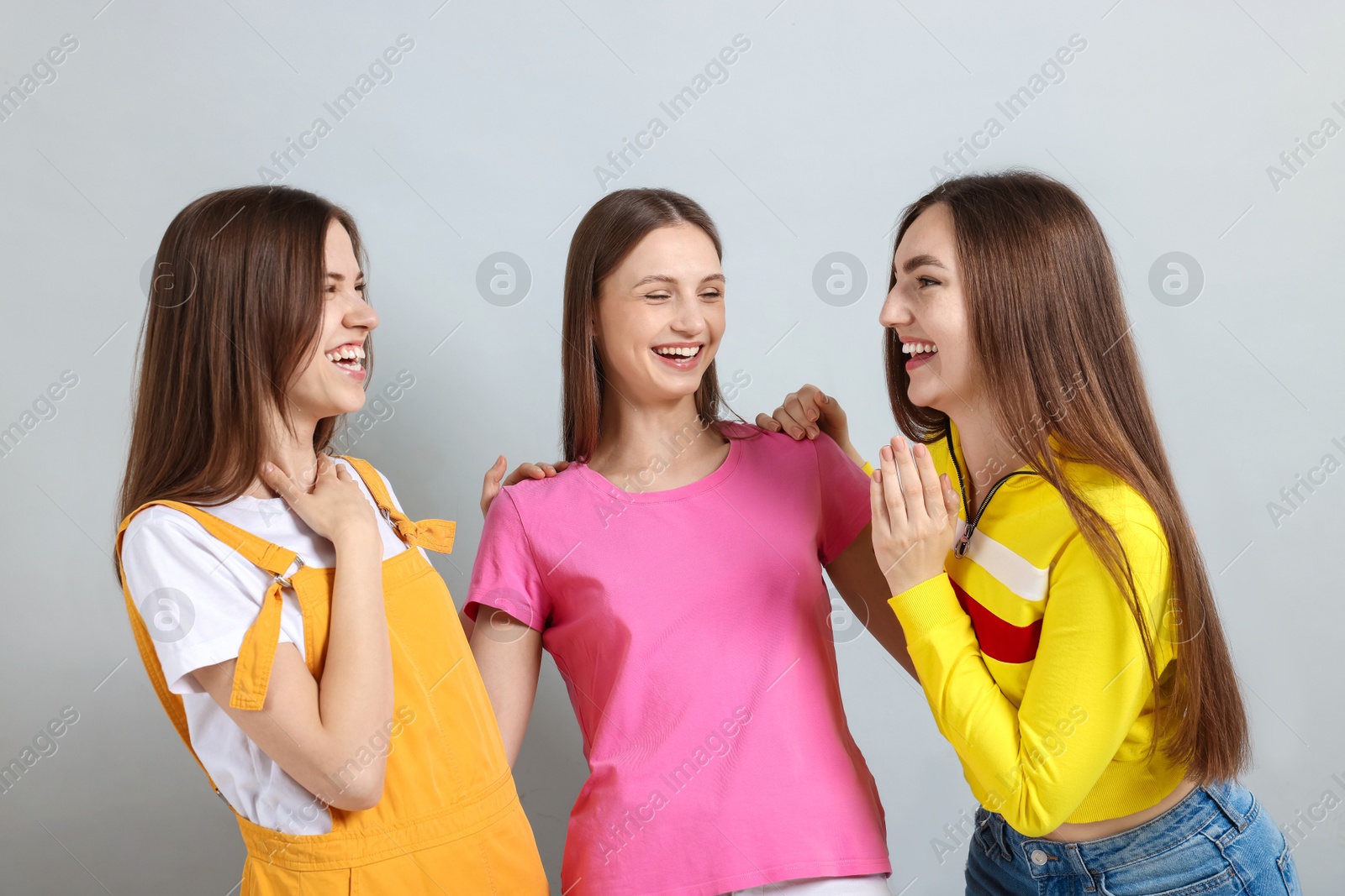 Friends hugging each other on light grey background Photo of Friends hugging each other on light grey background