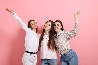 Photo of Friends hugging each other on pink background
