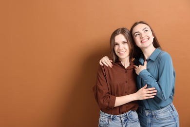 Photo of Friends hugging each other on pale brown background, space for text