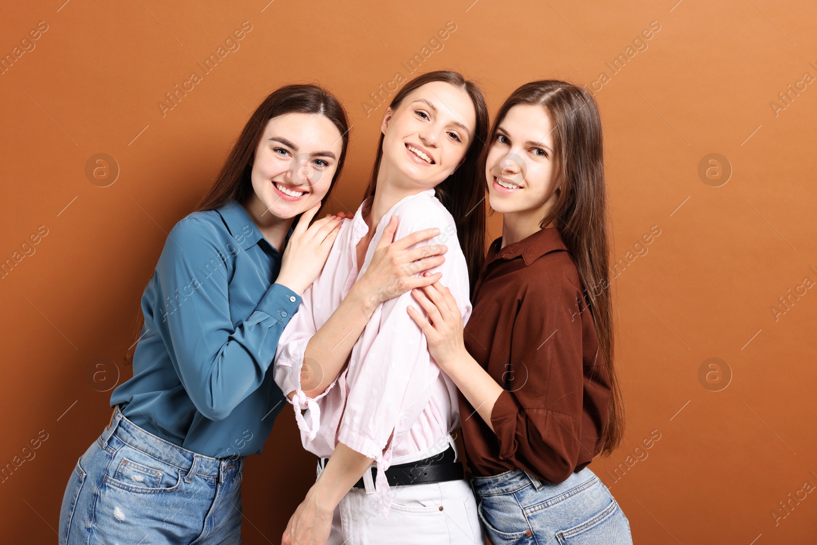 Photo of Friends hugging each other on pale brown background