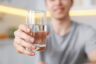 Photo of Man with glass of water in kitchen, selective focus