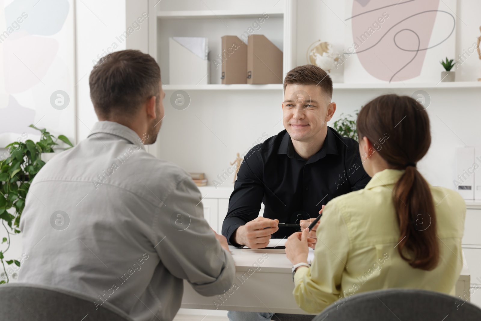 Couple having meeting with business consultant at table in office Photo of Couple having meeting with business consultant at table in office