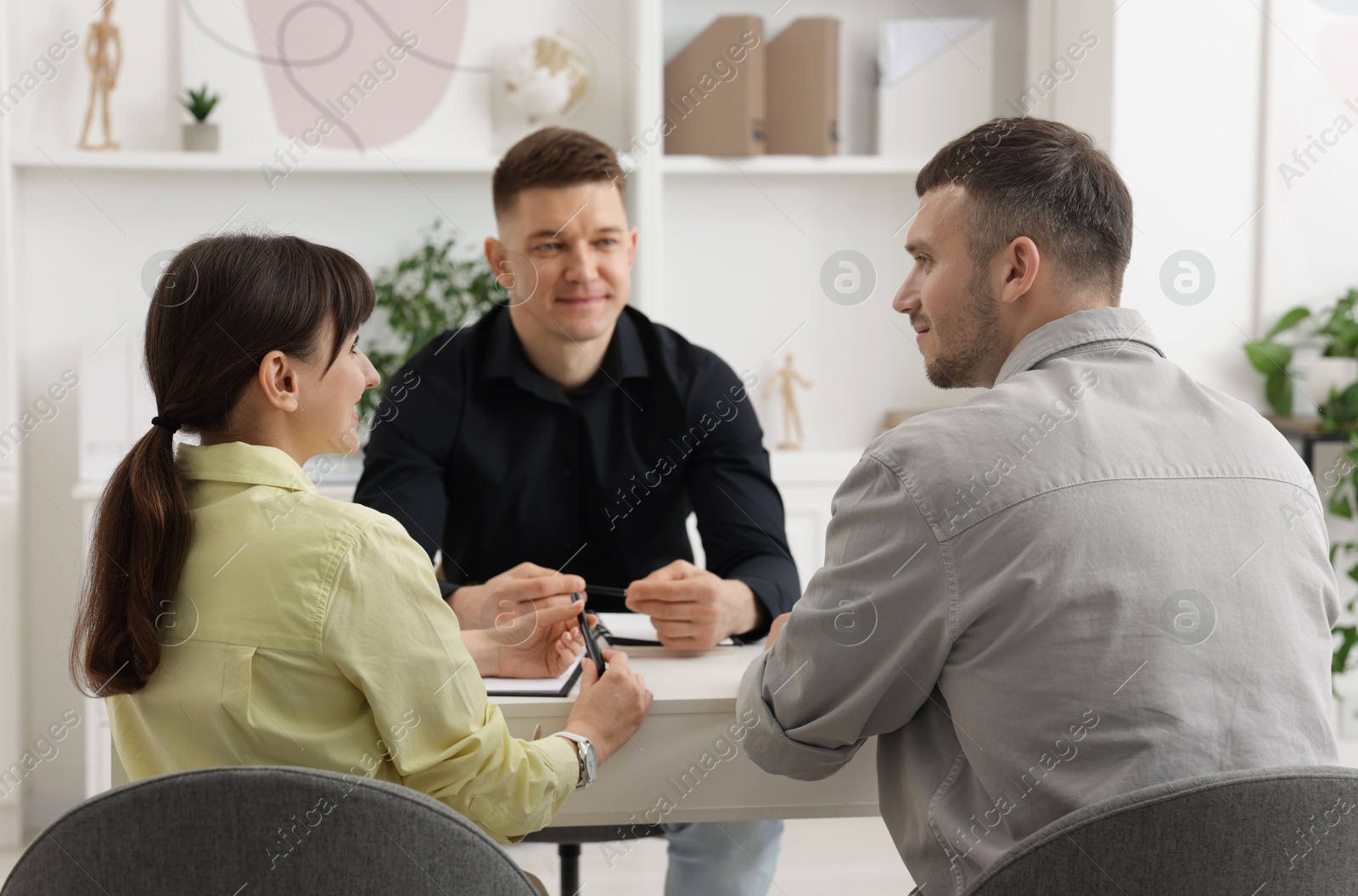 Couple having meeting with business consultant at table in office Photo of Couple having meeting with business consultant at table in office