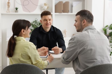 Photo of Couple having meeting with business consultant at table in office