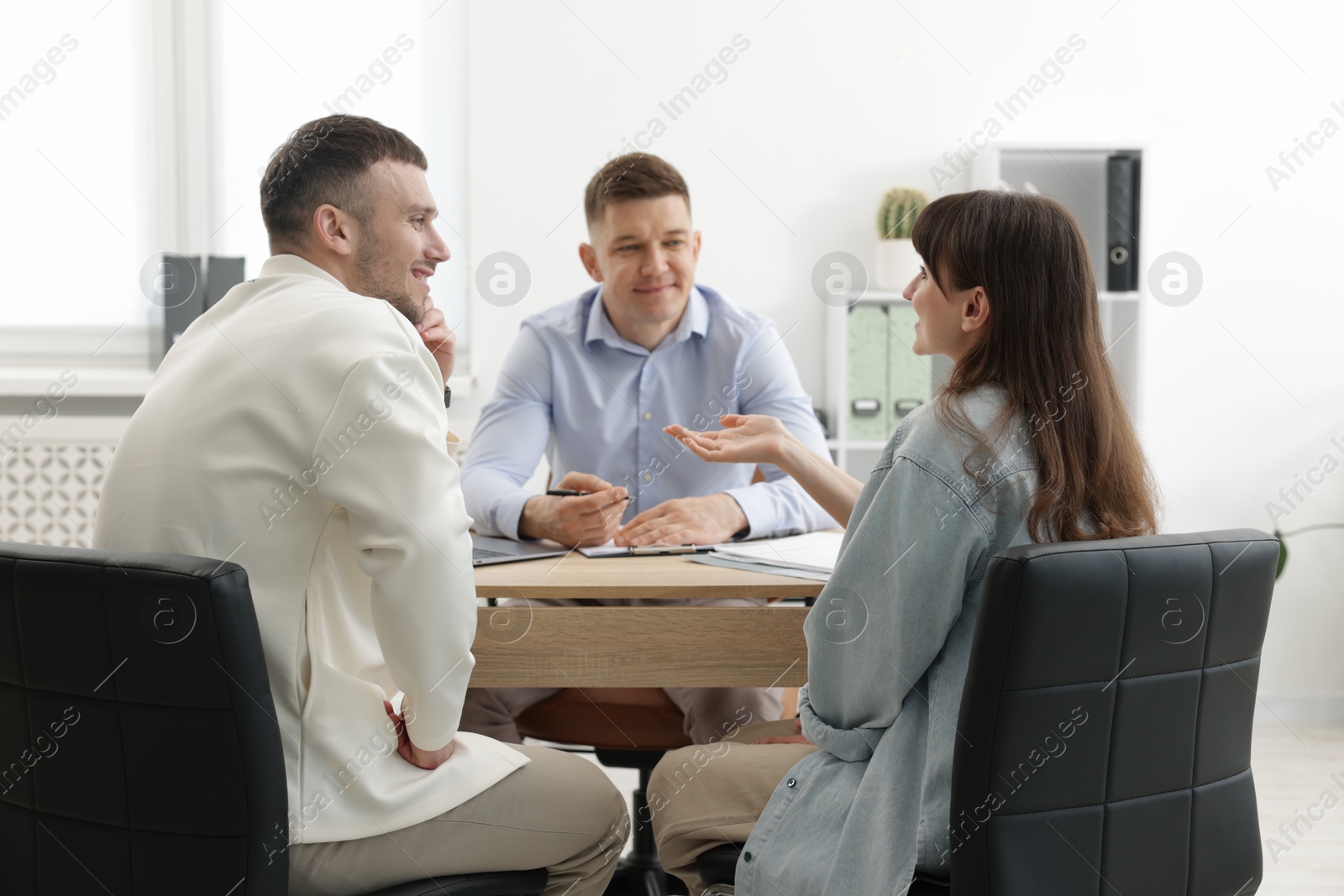 Photo of Couple having meeting with business consultant at table in office