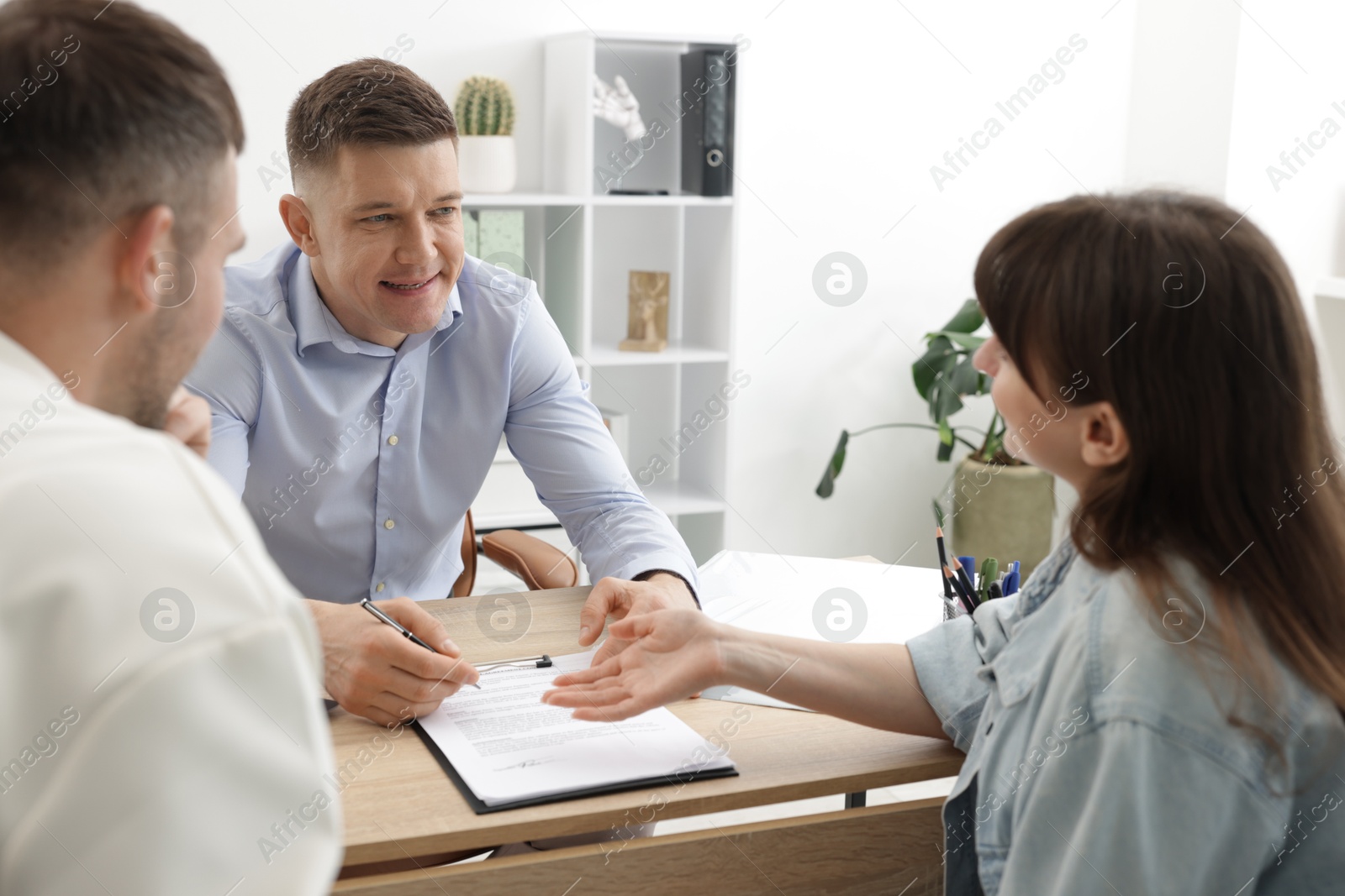 Couple having meeting with business consultant at table in office Photo of Couple having meeting with business consultant at table in office