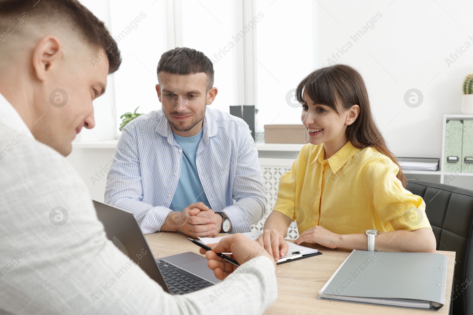 Photo of Couple having meeting with business consultant at table in office