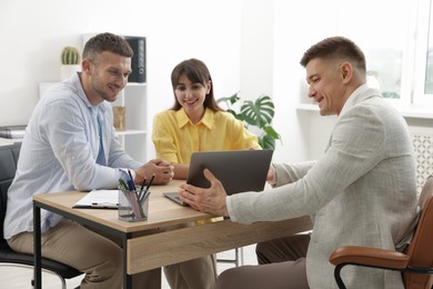 Photo of Couple having meeting with business consultant at table in office