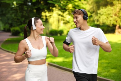 Photo of Sporty couple with headphones running in park
