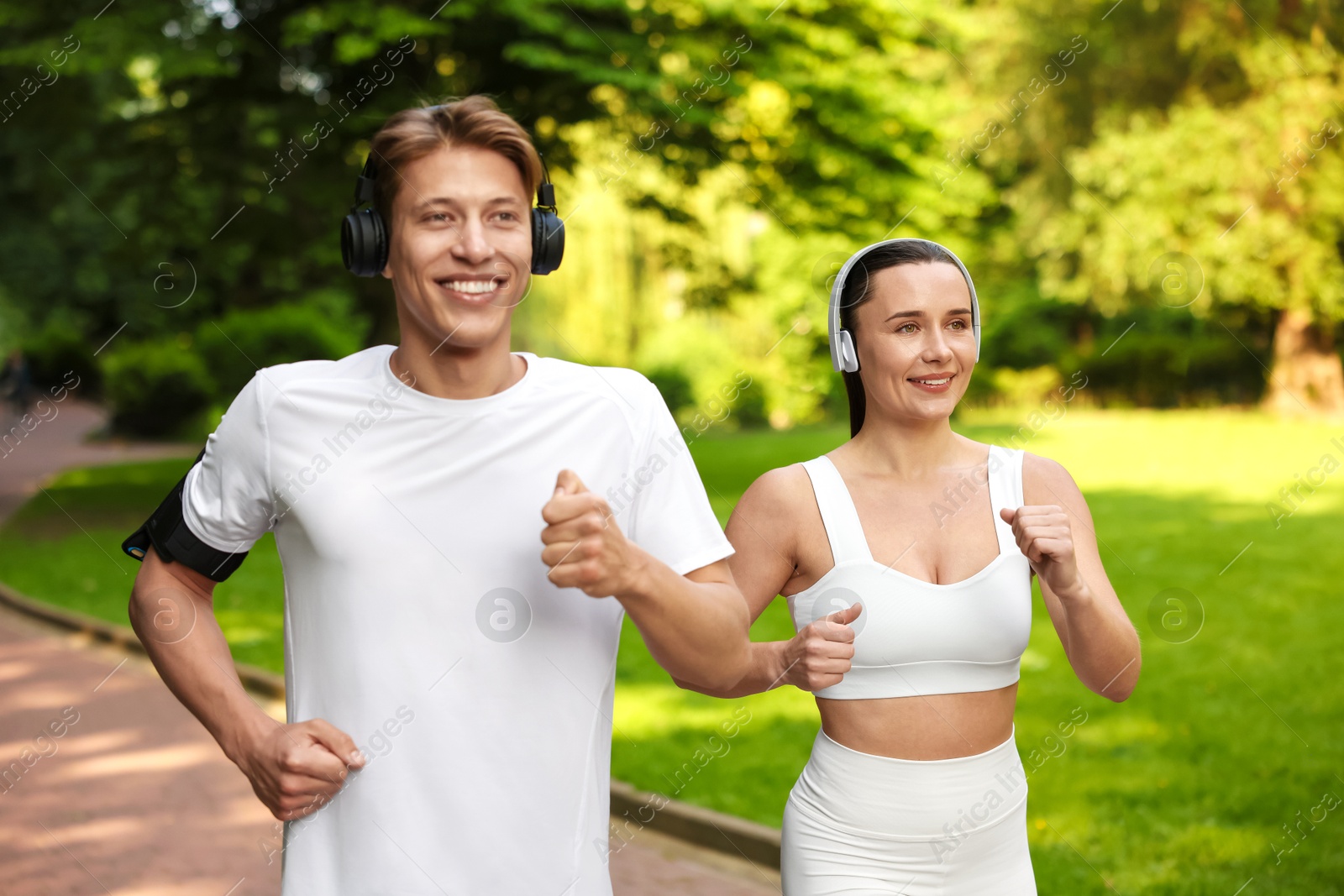 Photo of Sporty couple with headphones running in park