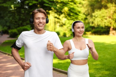 Photo of Sporty couple with headphones running in park