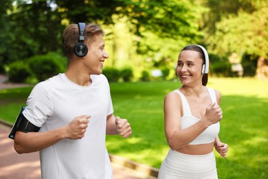 Photo of Sporty couple with headphones running in park