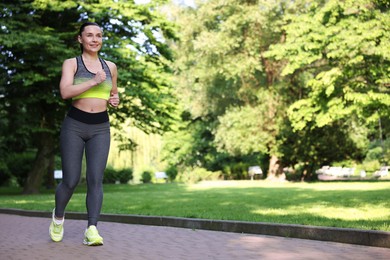 Photo of Sporty woman running in park, space for text