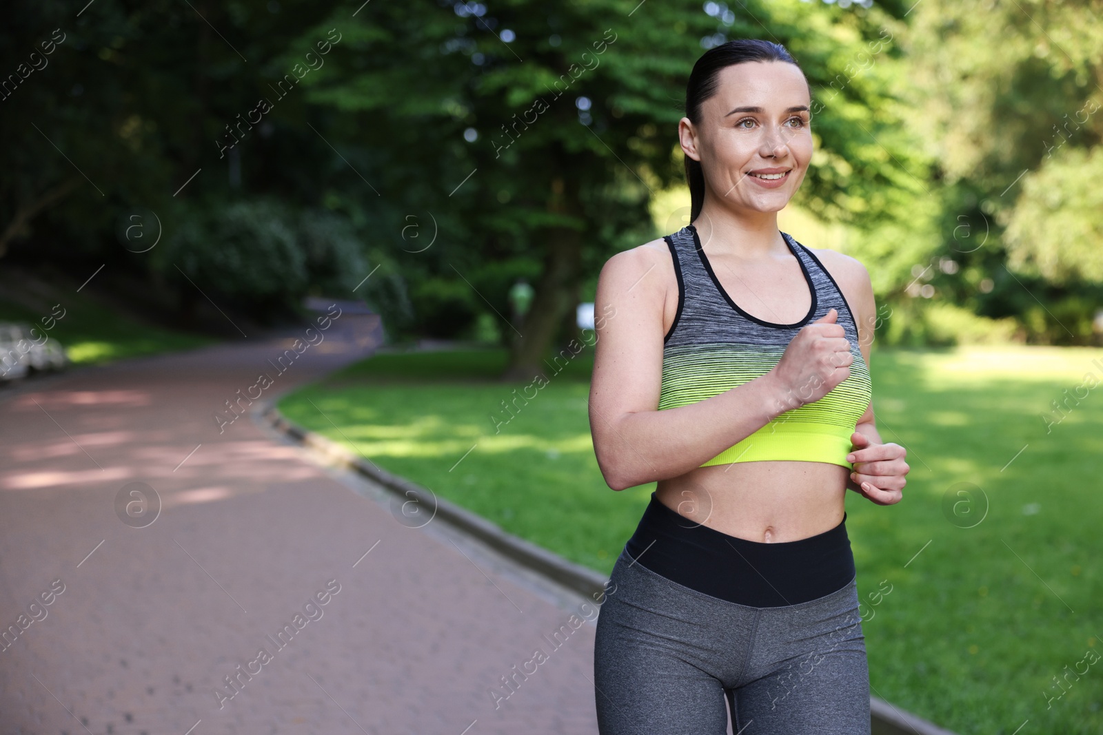 Sporty woman running in park, space for text Photo of Sporty woman running in park, space for text