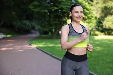 Photo of Sporty woman running in park, space for text